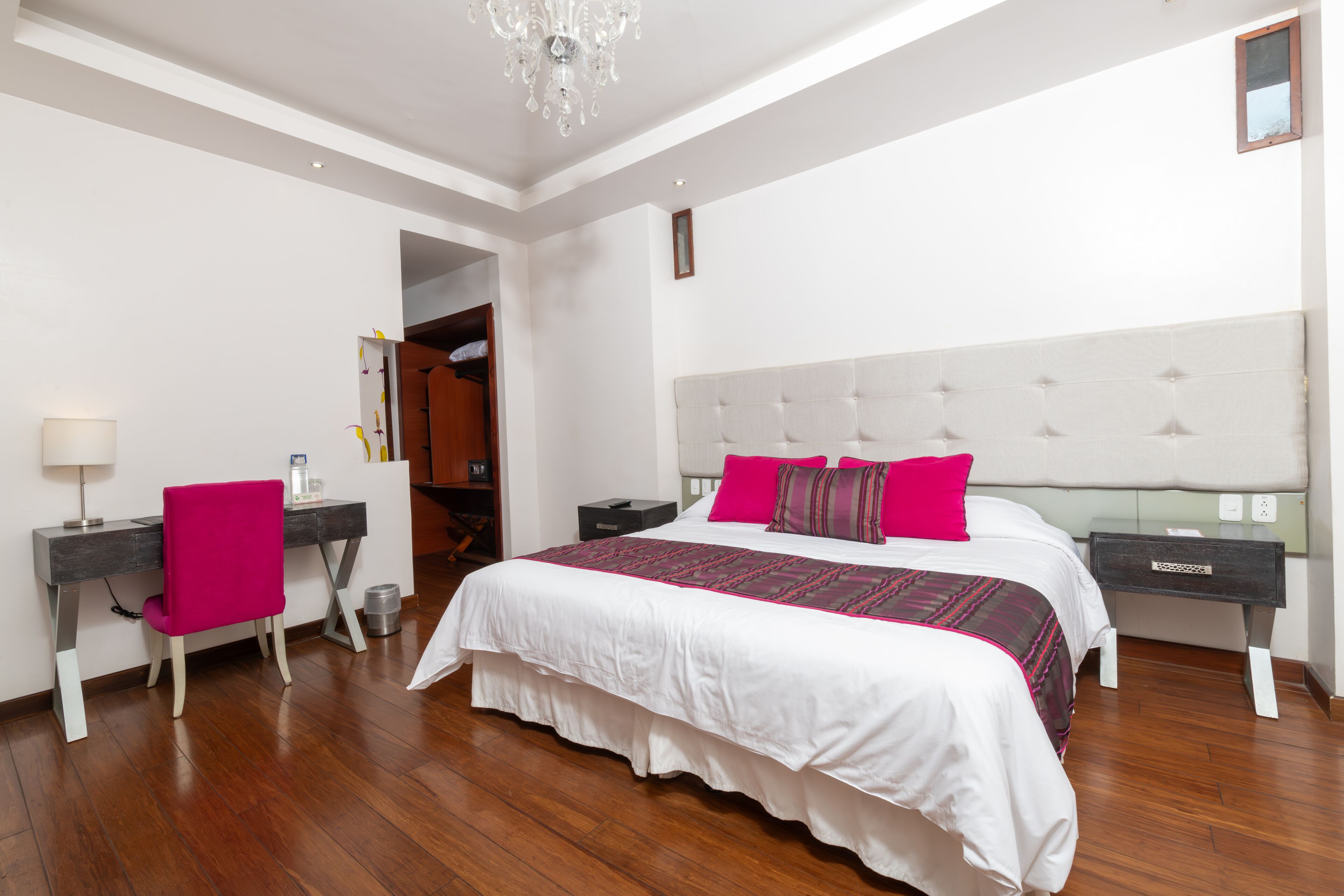 A bedroom with a large bed, a desk, a chair, and a wardrobe.