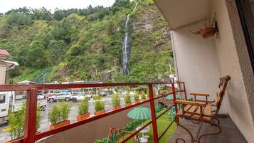 Un balcón con vista a una cascada, un estacionamiento y un césped verde con plantas en macetas.