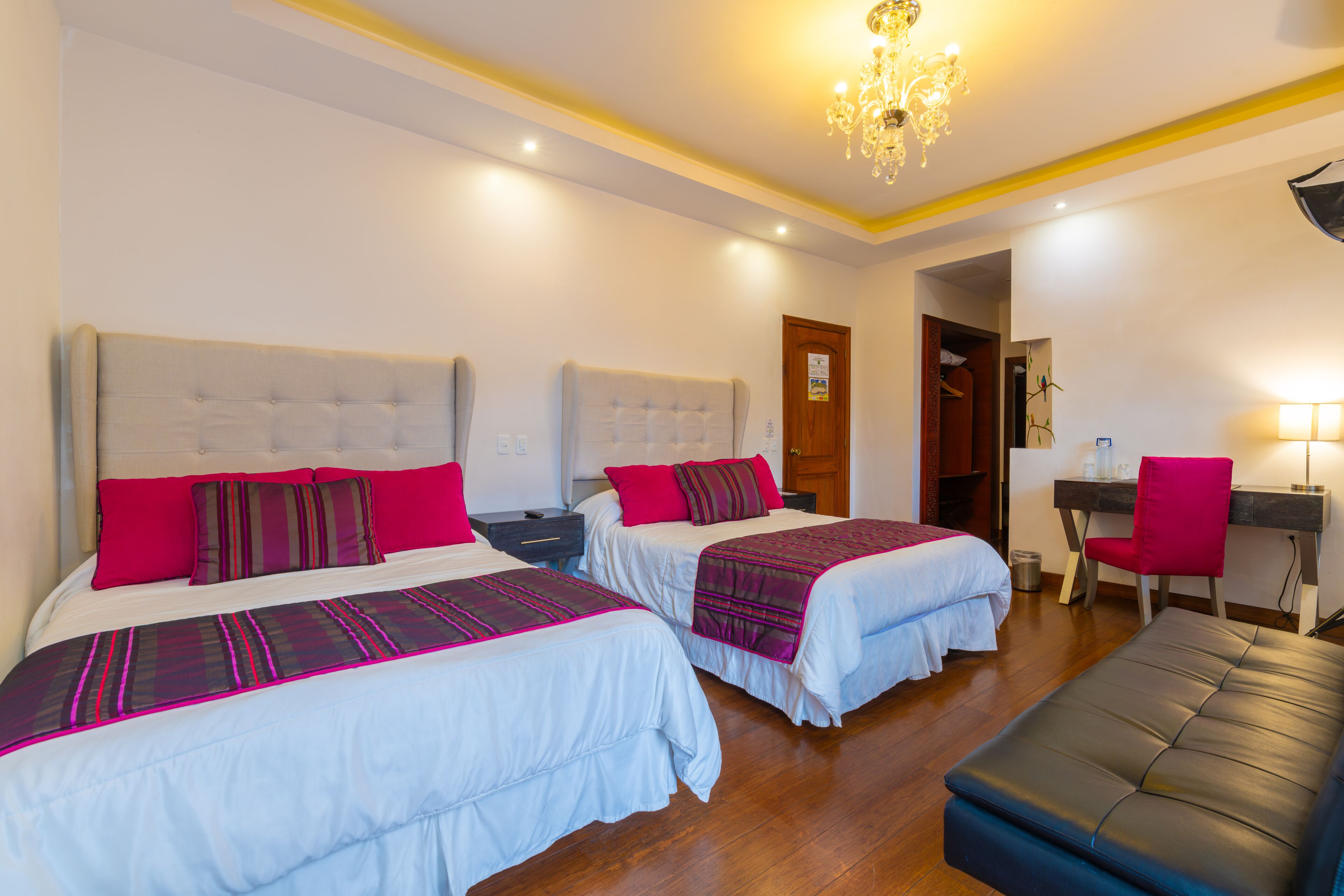 Habitación de hotel con dos camas, un escritorio, una silla y un banco.