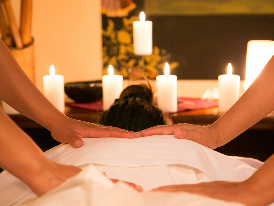 A massage therapy session with a person lying face down and receiving a back massage.