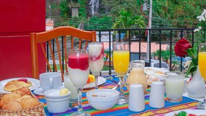 Una mesa de desayuno con diversos platos, bebidas y vistas a una cascada.