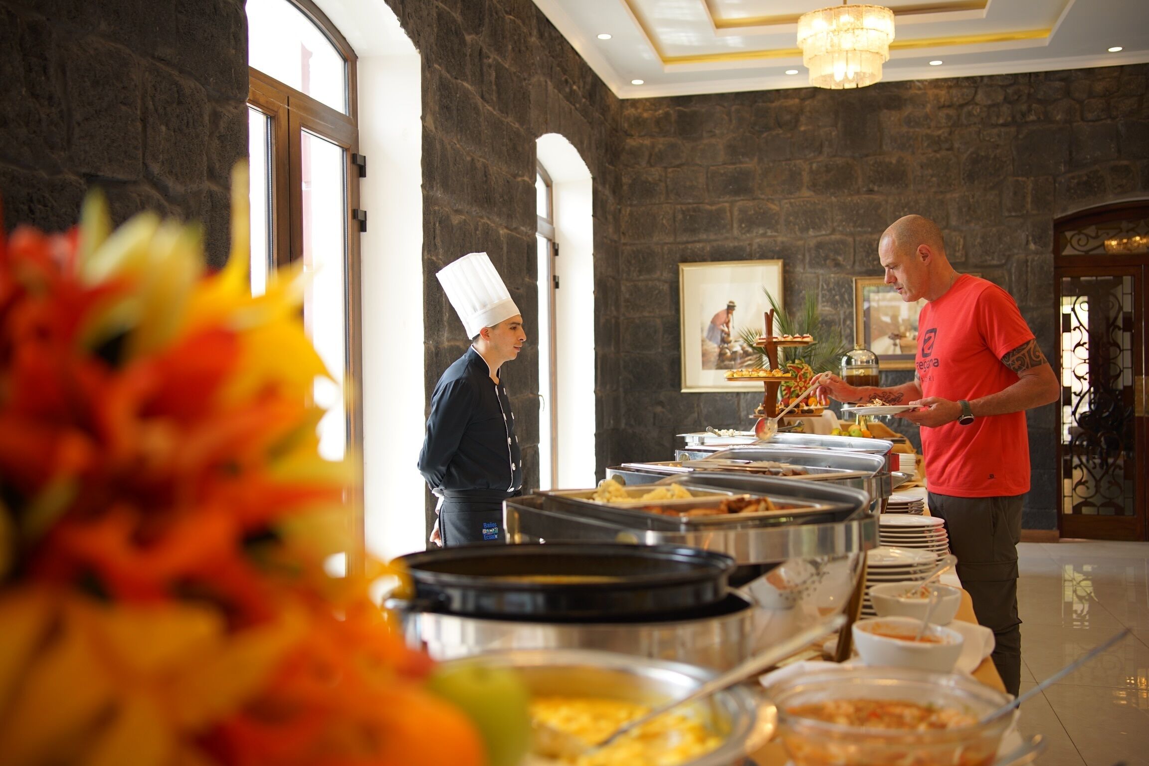 A buffet setup with multiple food stations, a chef in uniform, and a person serving food.