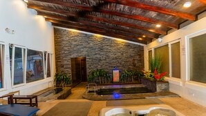 Un área de spa con pared de piedra, tinaco y camilla de masaje.