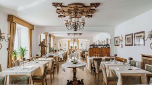 Ein Restaurant mit mehreren Tischen und Stühlen, einer Kandelaber und einem Spiegel mit dekorativem Rahmen.
