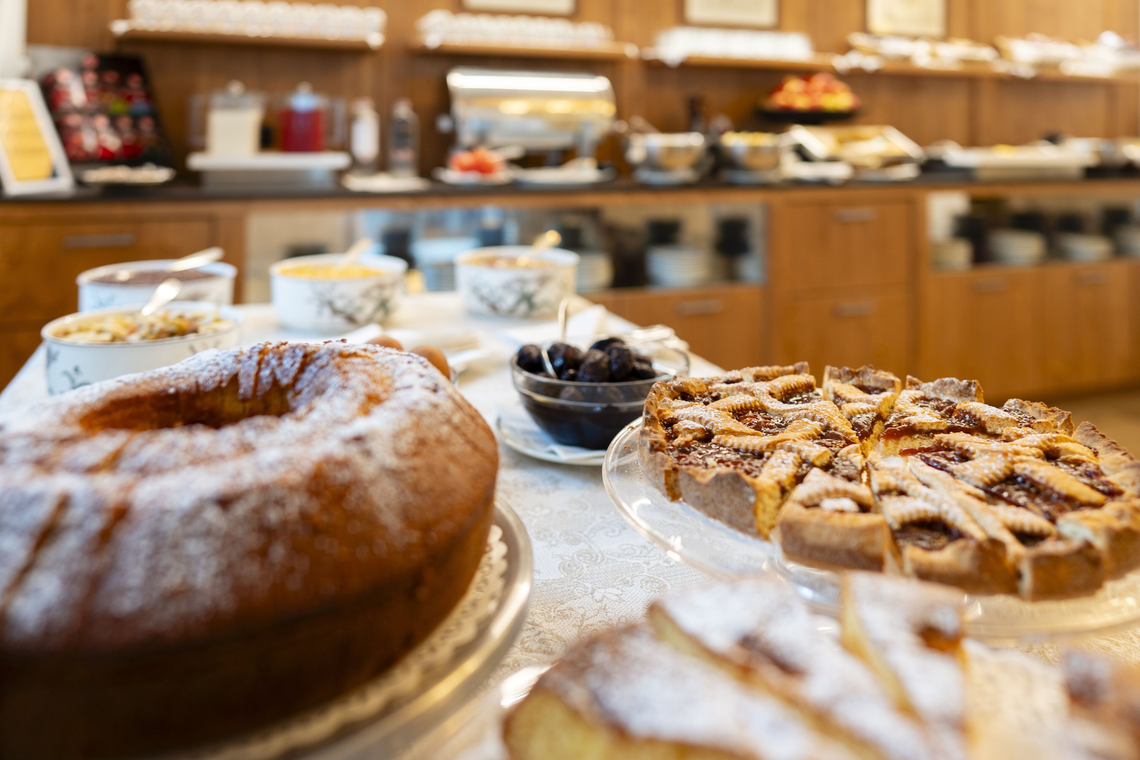 Una mesa de buffet con diversos postres, incluyendo un pastel Bundt y una tarta de frutas.