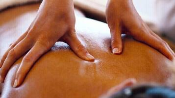 Gros plan sur des mains effectuant un massage sur le dos d’une personne.