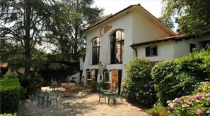 A two-story building with a garden patio, outdoor seating, and a fountain.