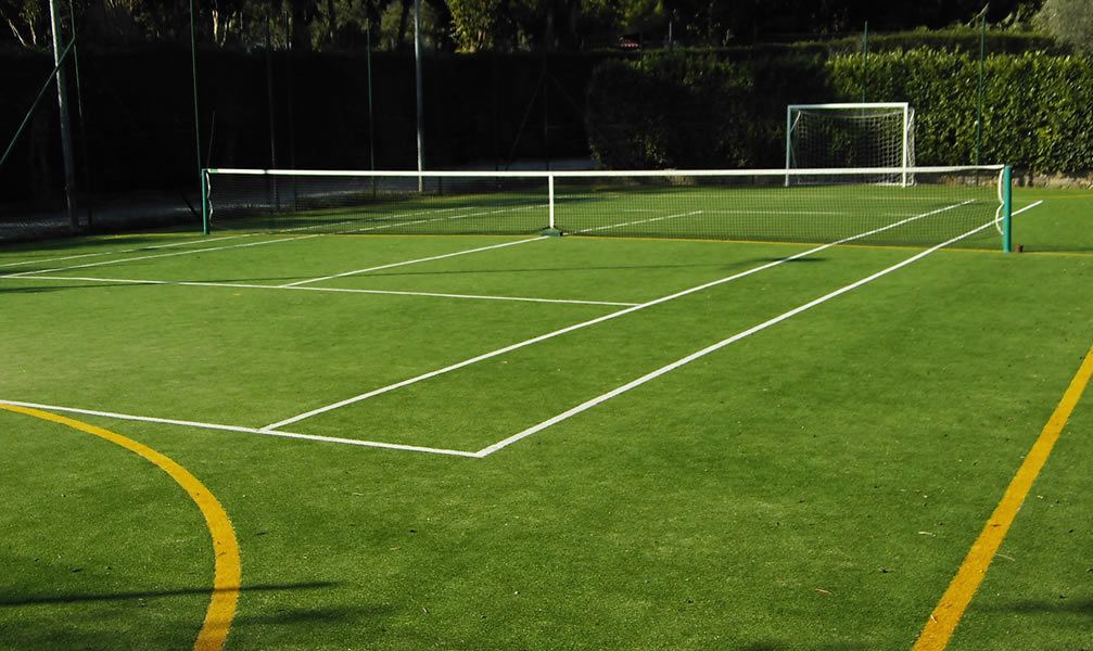 A tennis court with a net, boundary lines, and a goalpost.