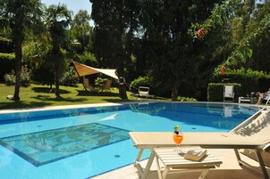 Una piscina al aire libre de temporada, sillones reclinables de piscina