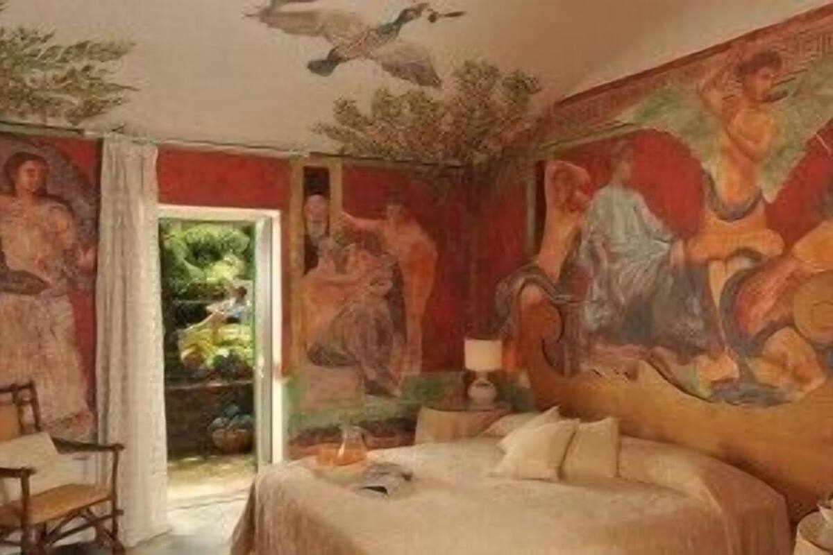 Een slaapkamer met een groot bed, een stoel en een muurschildering.