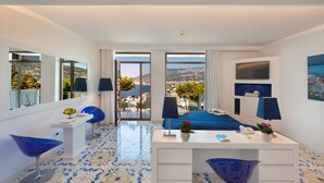 Un hotel moderno con una cama grande, un escritorio con teléfono y vistas a la ciudad a través de amplias ventanas.