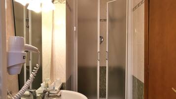 Bagno con lavandino, specchio, asciugacapelli e cabina doccia.