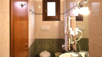 A bathroom with a wooden door, a toilet, a bidet, and a sink with a mirror.