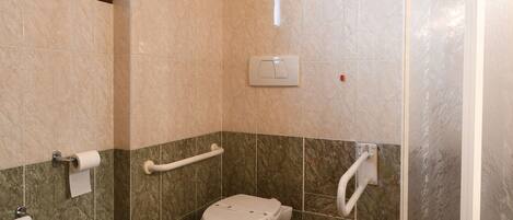 A bathroom with a toilet, bidet, and shower.