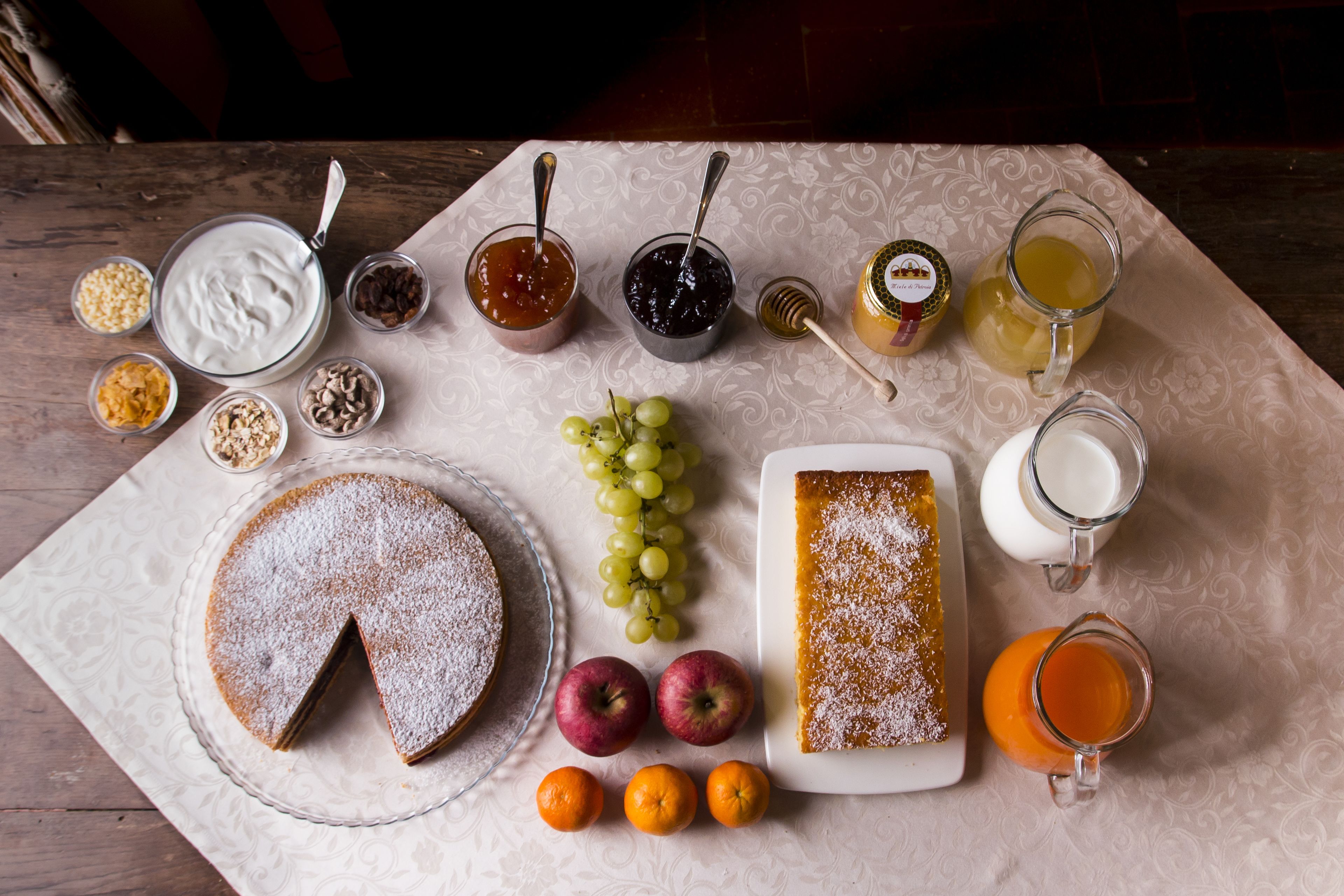 Una mesa con diversos alimentos, incluyendo un pastel, frutas y salsas.