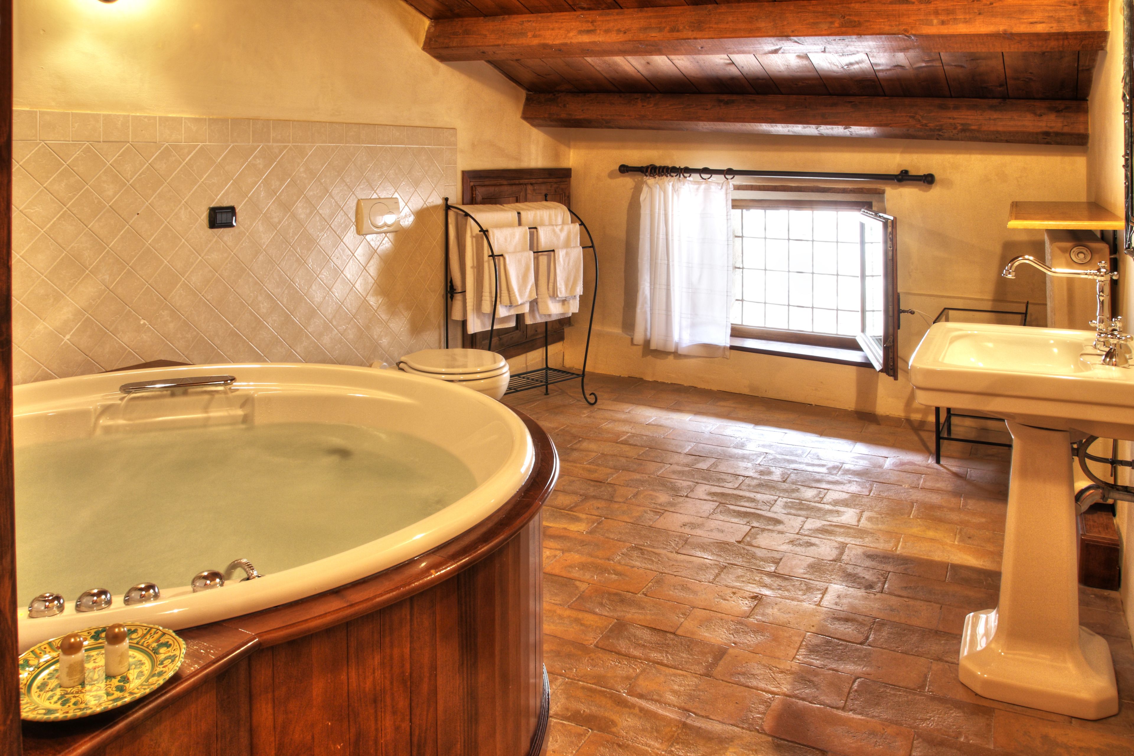 A bathroom with a large bathtub, a sink, and a window with curtains.