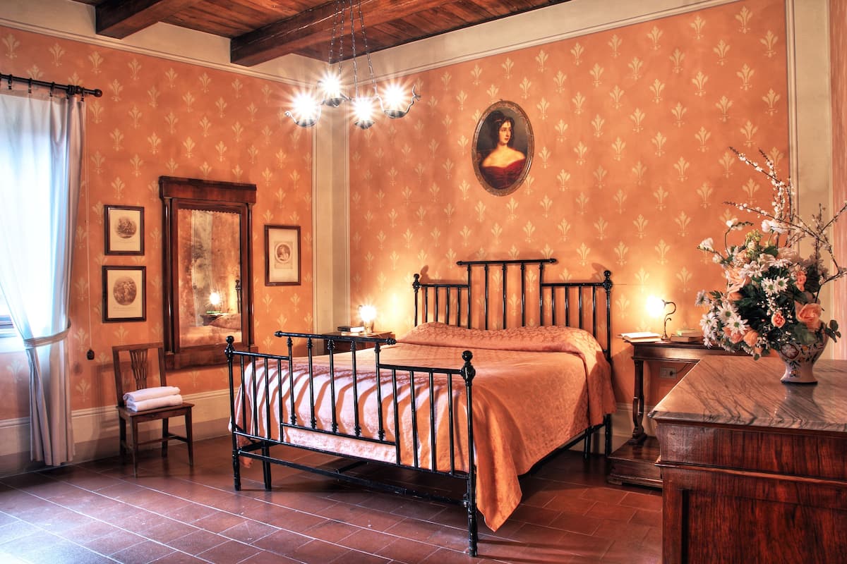 A traditional room with a bed, a chair, a dresser, and a mirror.