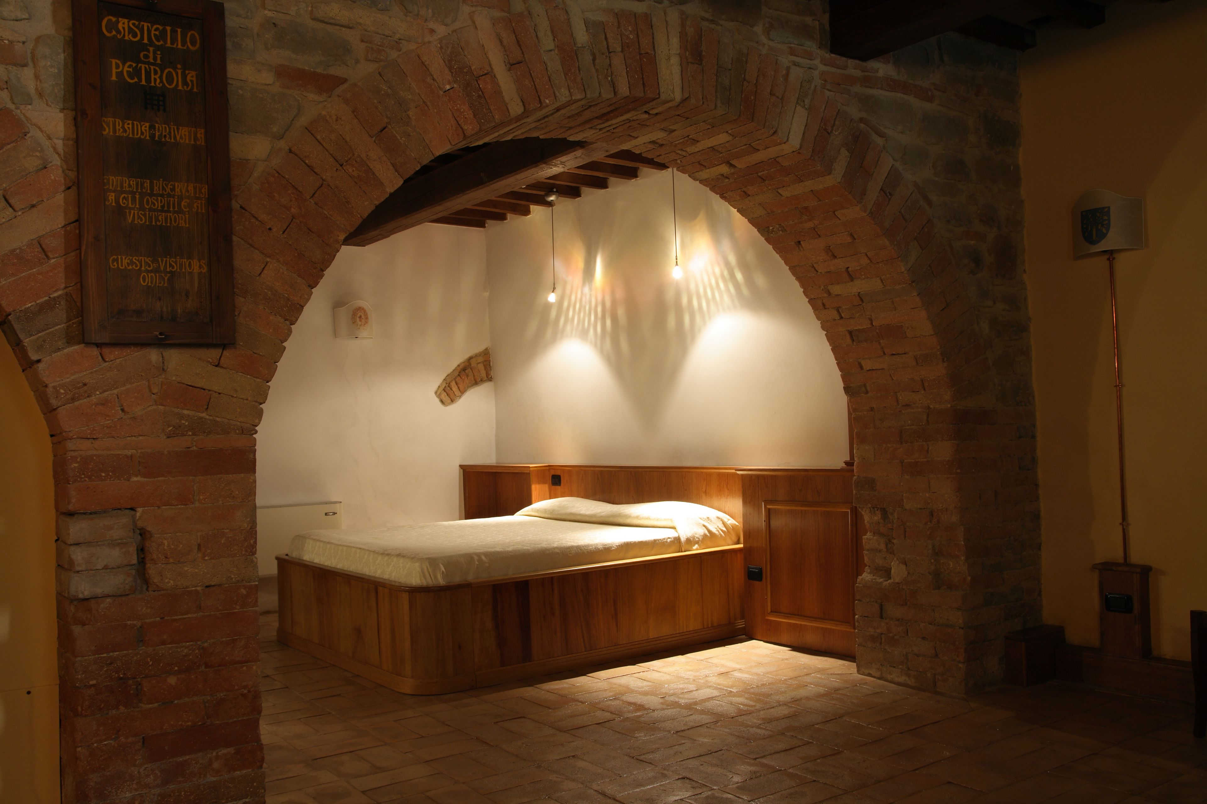 Ein Schlafzimmer mit einem hölzernen Bett, Ziegelwänden und einem Steingewölbe.