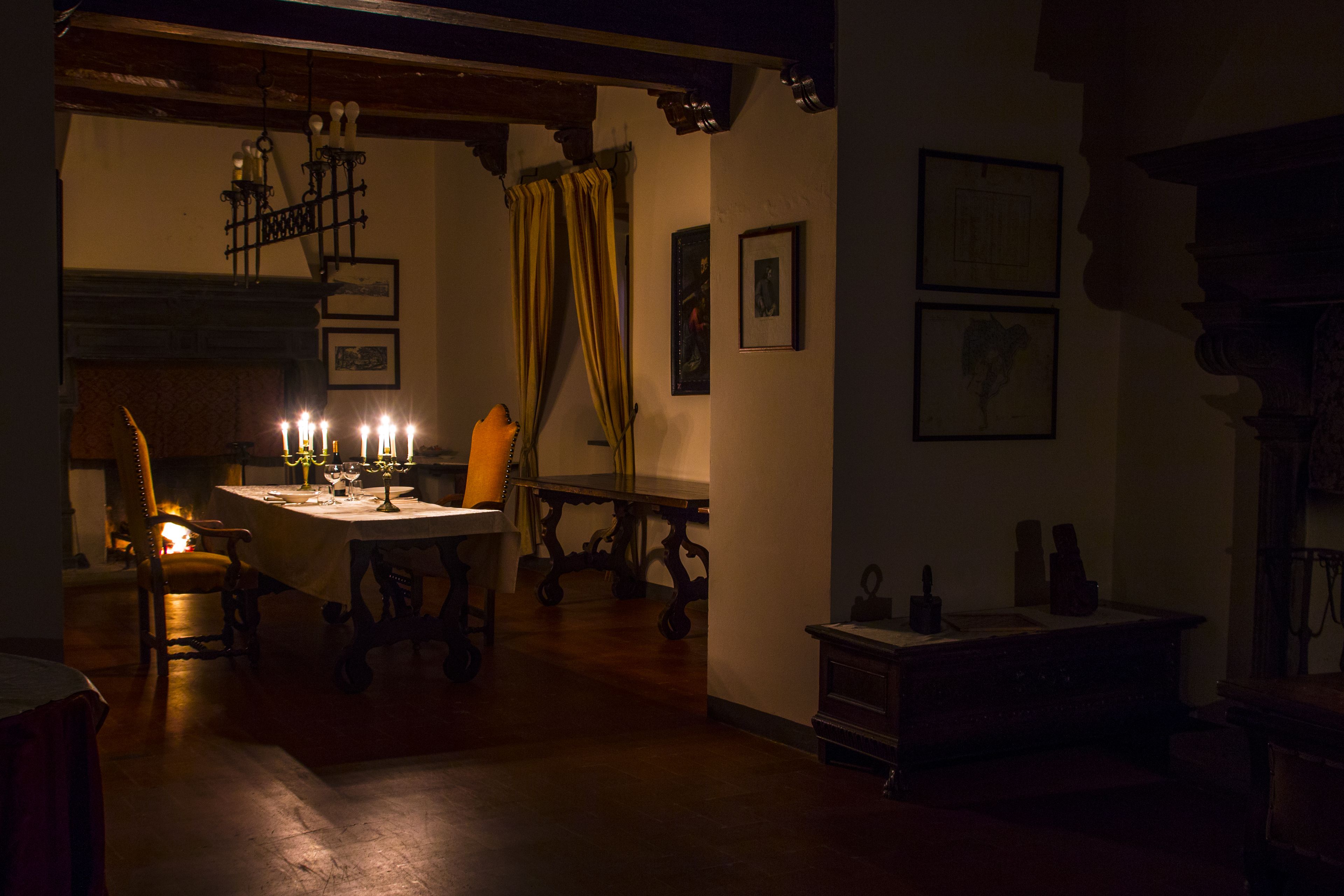 A dimly lit room with a table set for dining, a chair, and a fireplace.