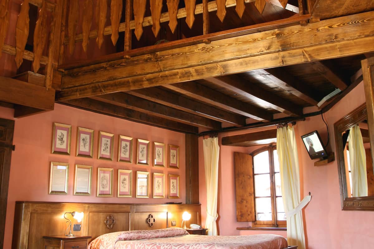 A wooden bedroom with a large bed, a chandelier, and a balcony.