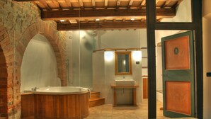 A bathroom with a wooden bathtub, a sink, and a mirror. - Castello Di Petroia Relais (Gubbio)