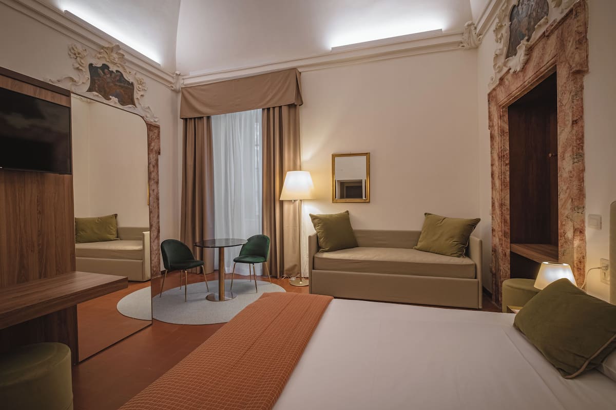 A hotel room with a bed, two sofas, a table, and a chair.