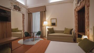 A hotel room with a bed, two sofas, a table, and a chair.