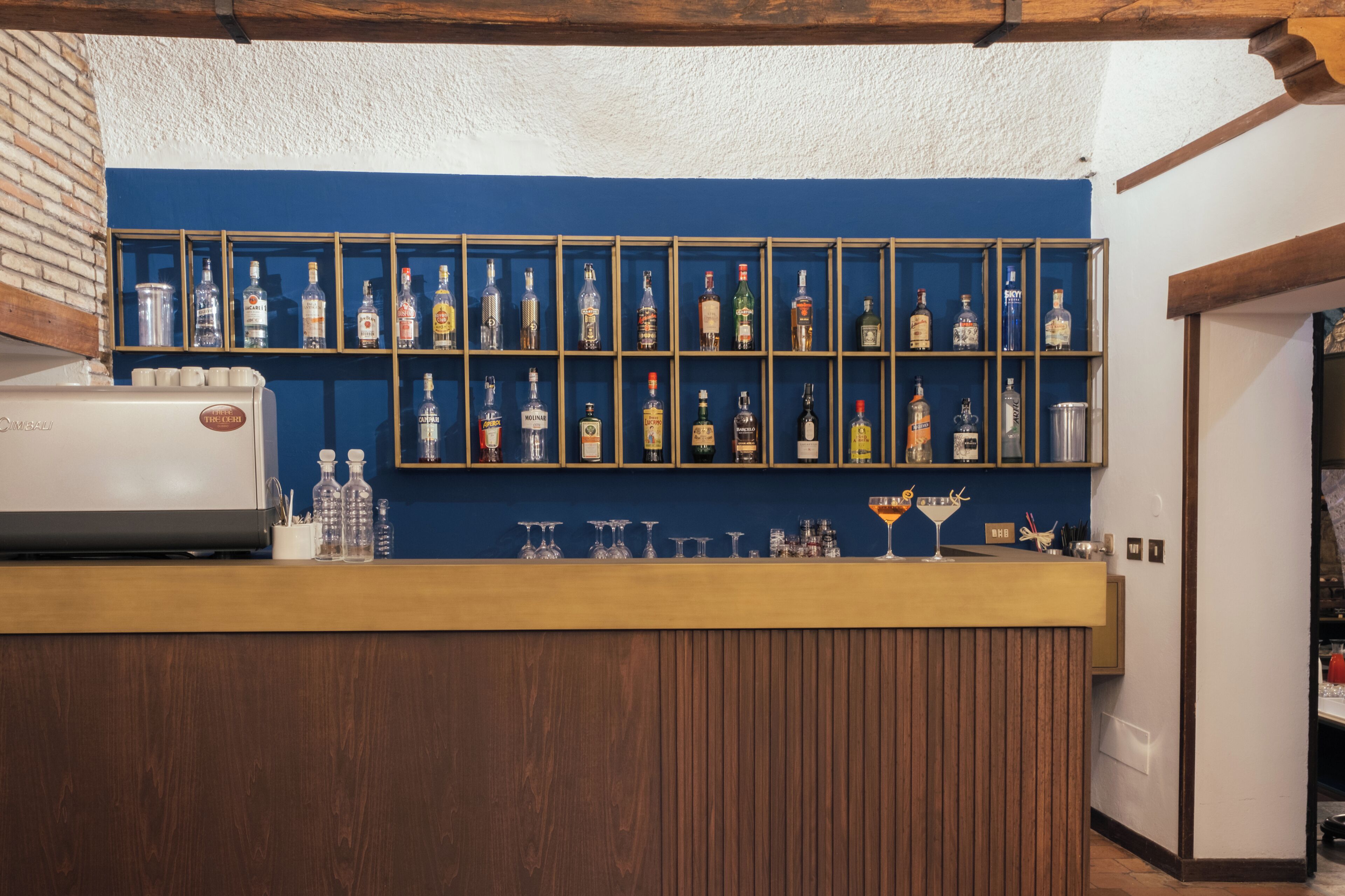 Un espace bar avec un comptoir en bois et des étagères remplies de différentes bouteilles de spiritueux.
