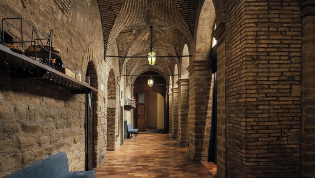 A corridor with stone walls, wooden benches, and a tiled floor. - Hotel Villa Montegranelli (Gubbio)