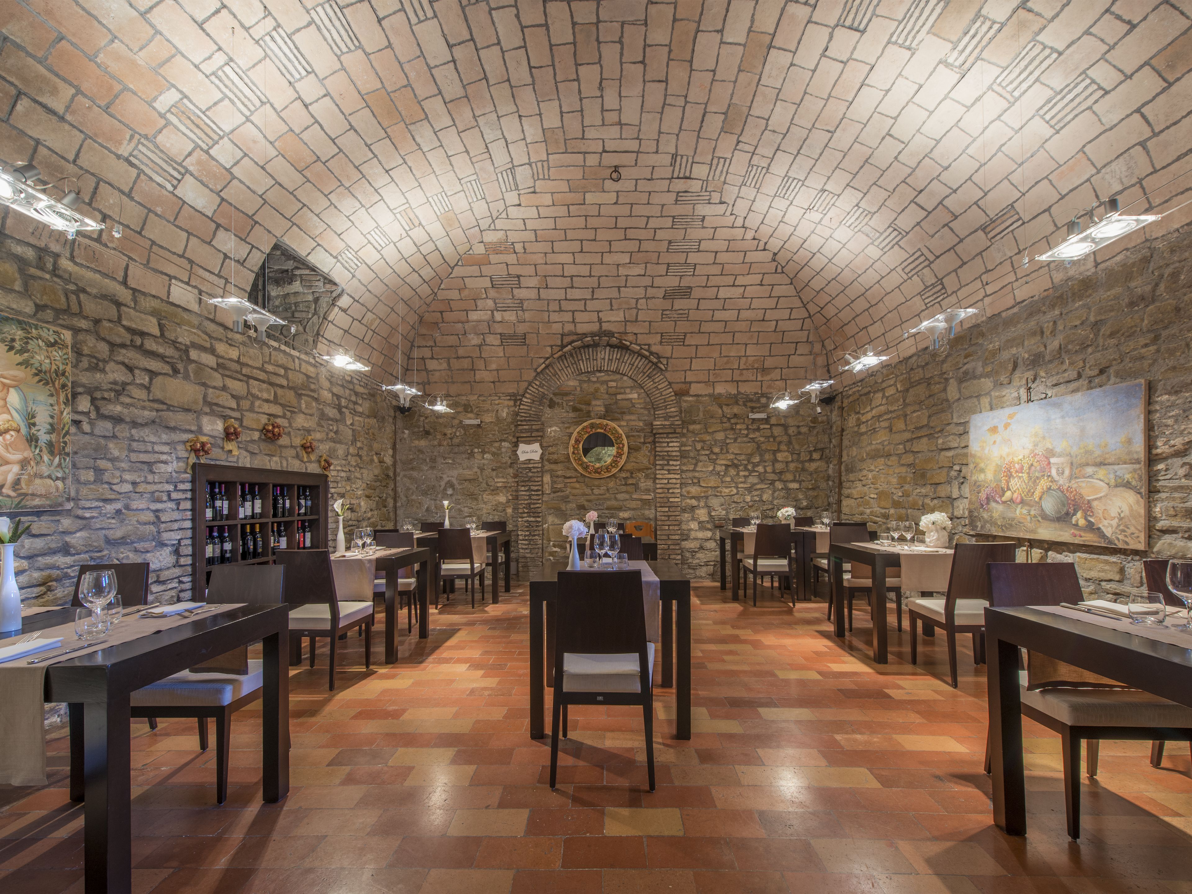 A restaurant with stone walls, wooden tables, and chairs.