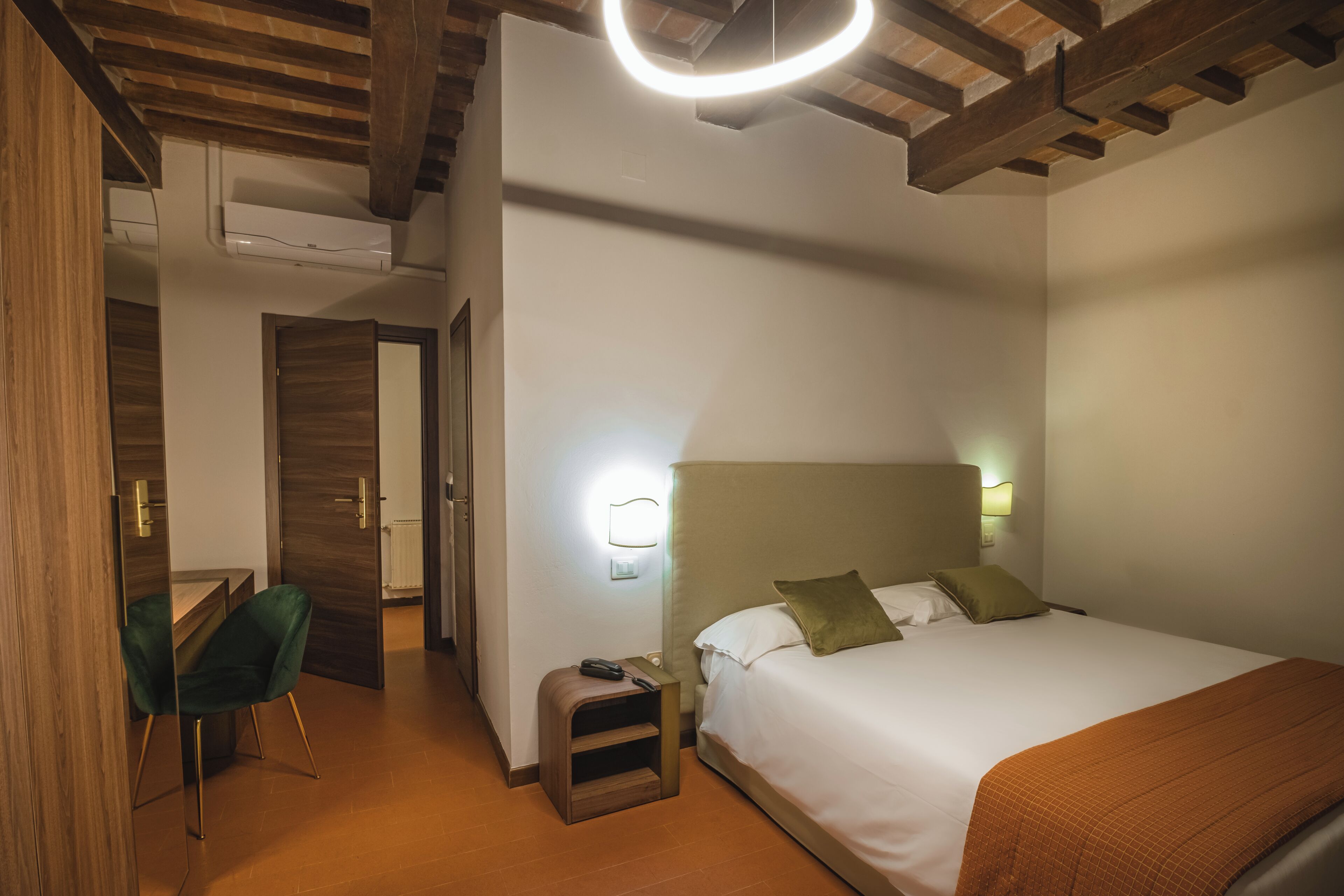 Une chambre d’hôtel comprenant un lit, une table de chevet, une commode, une chaise et un bureau.
