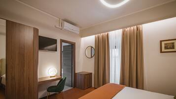 Una habitación de hotel moderna con una cama, un escritorio con silla, un espejo y una mesita de noche.