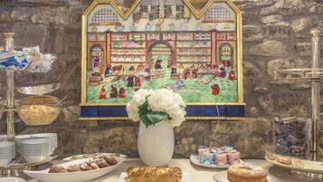A buffet table with various food items and a decorative wall painting.