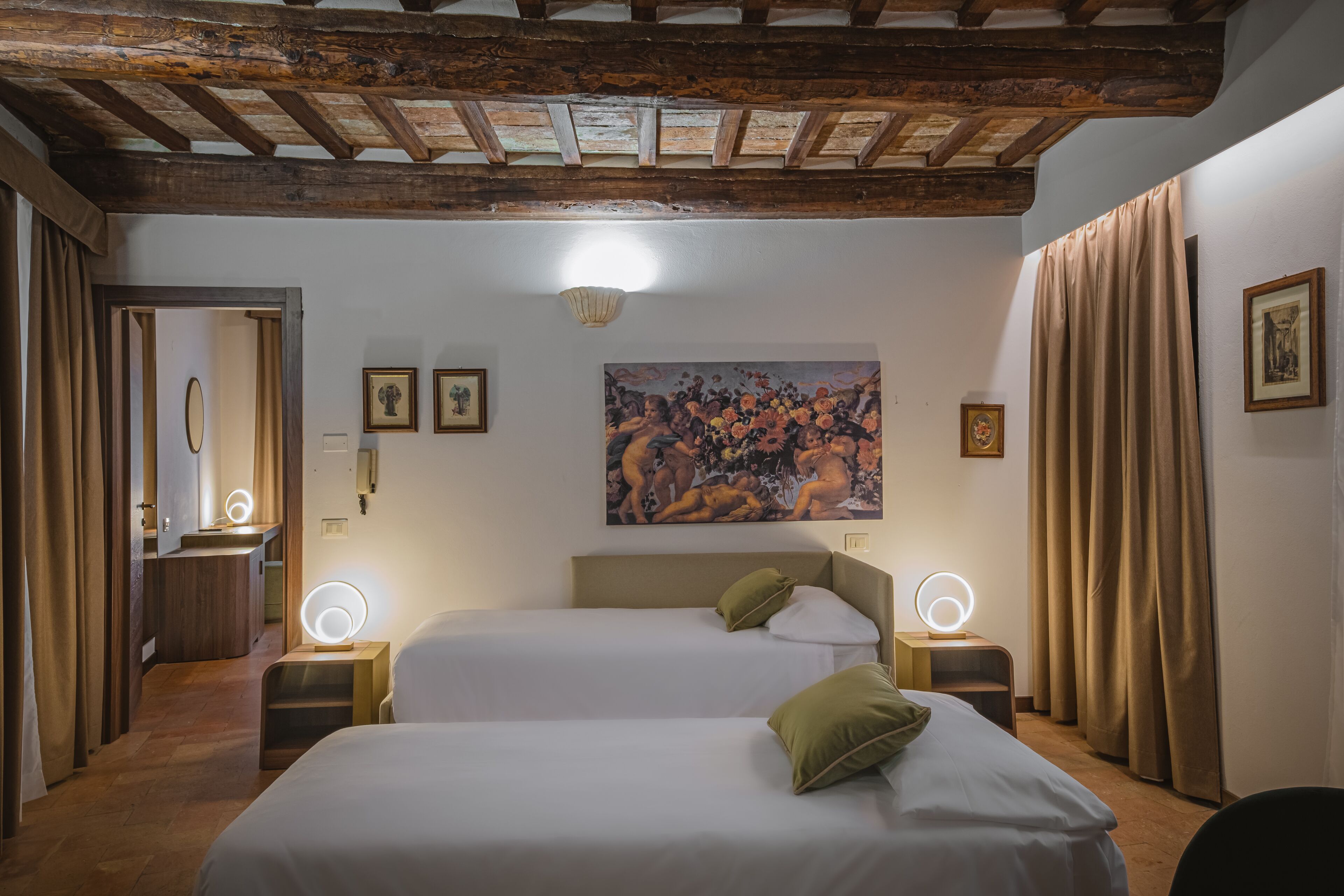 Una habitación de hotel con dos camas, un cuadro en la pared y un techo con vigas a la vista.