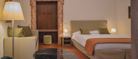 A hotel room with a bed, a sofa, a table, and a lamp.