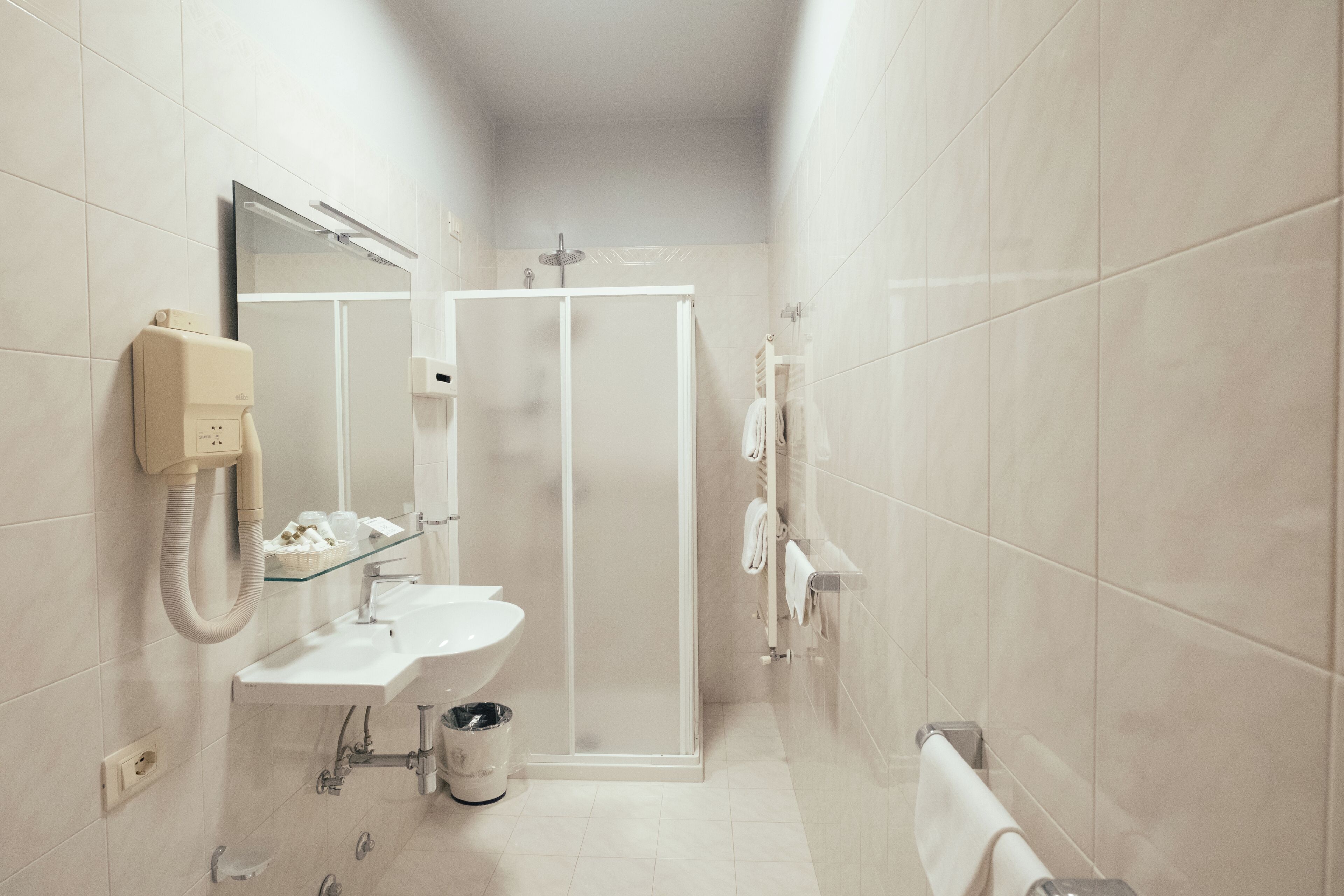 Ein modernes Badezimmer mit Duschkabine aus Glas, Waschbecken mit Spiegel und Handtuchhalter.