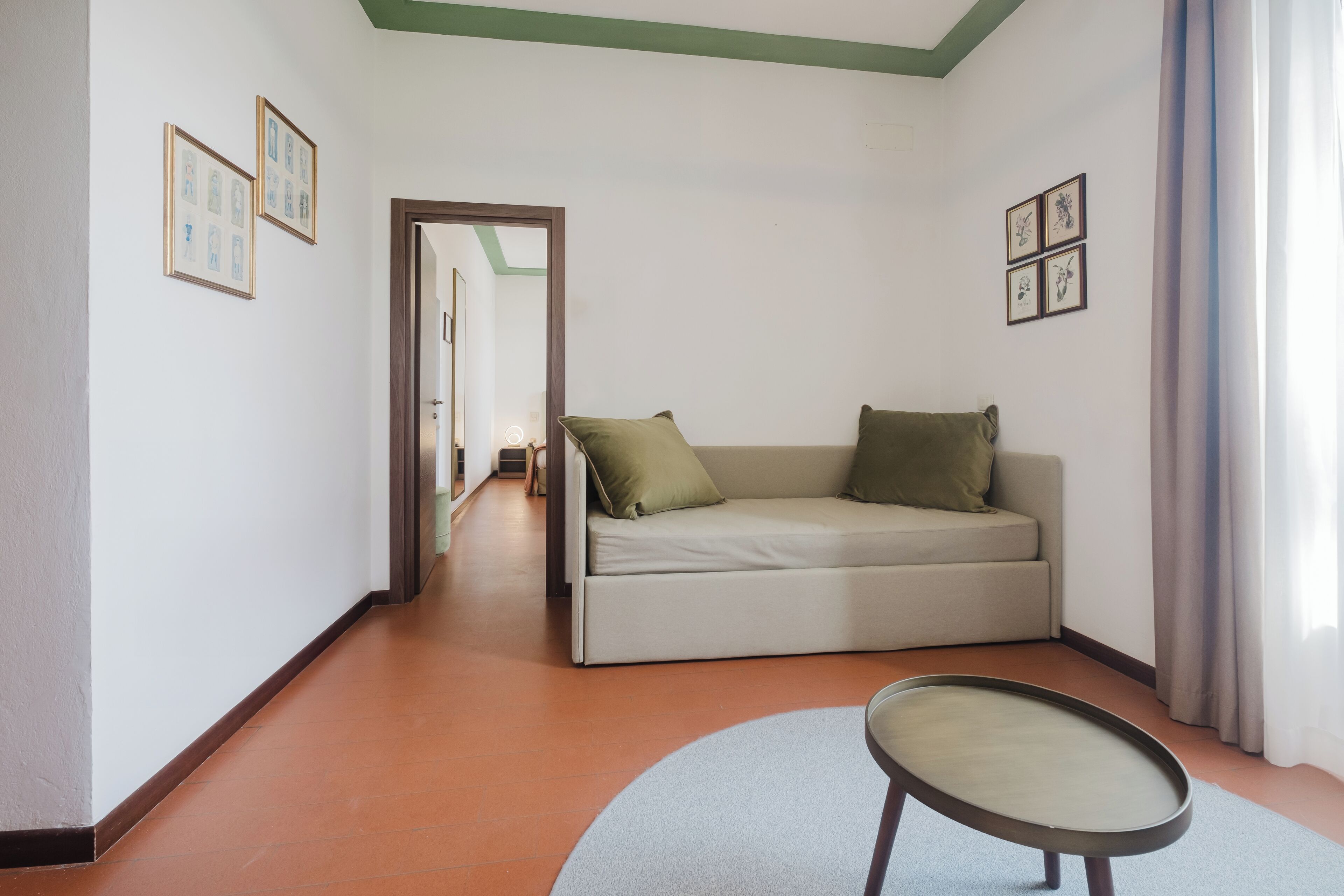 Una habitación con un sofá, una mesa redonda y cuadros en las paredes.