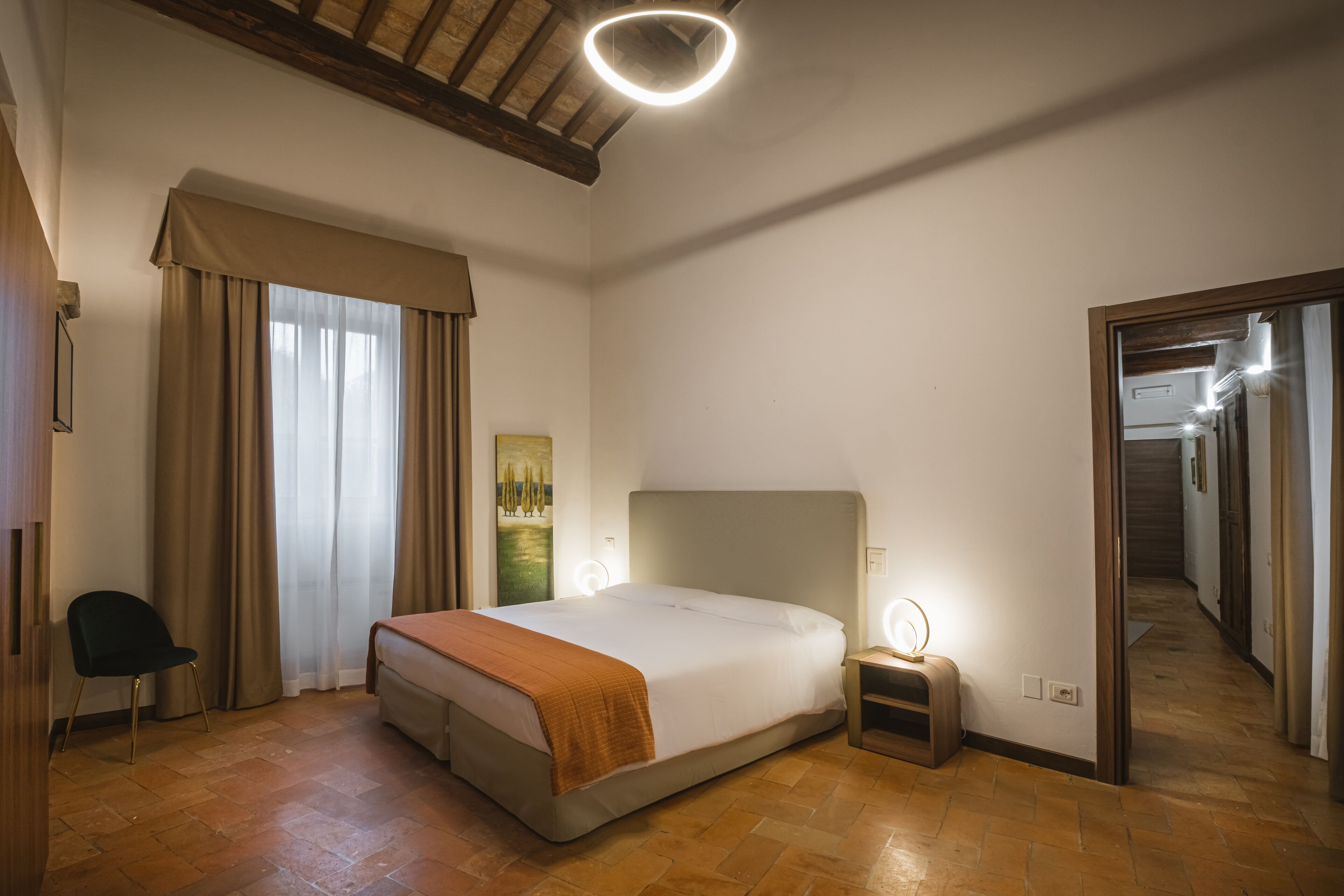 A bedroom with a large bed, a nightstand, a chair, and a mirror.