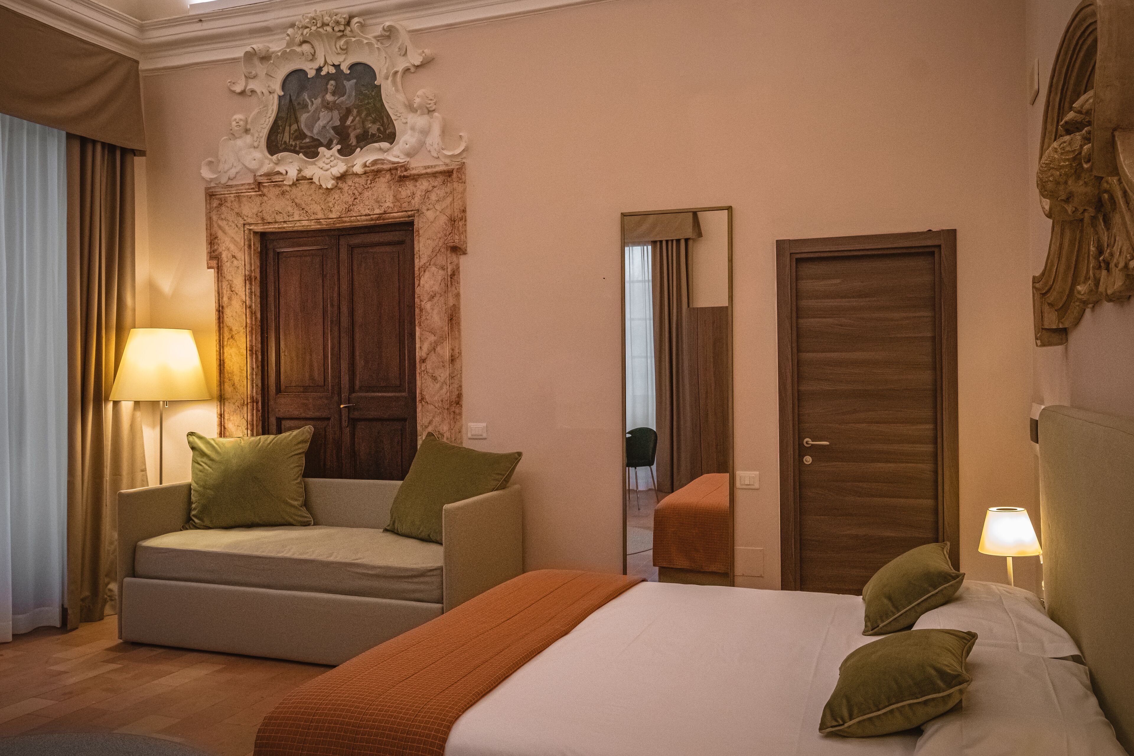 Una habitación de hotel con cama, sofá, espejo y puerta.
