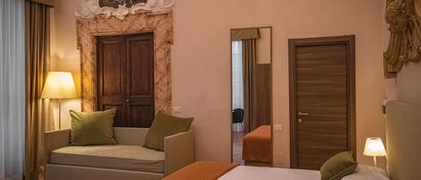 Una habitación de hotel con cama, sofá, espejo y puerta.