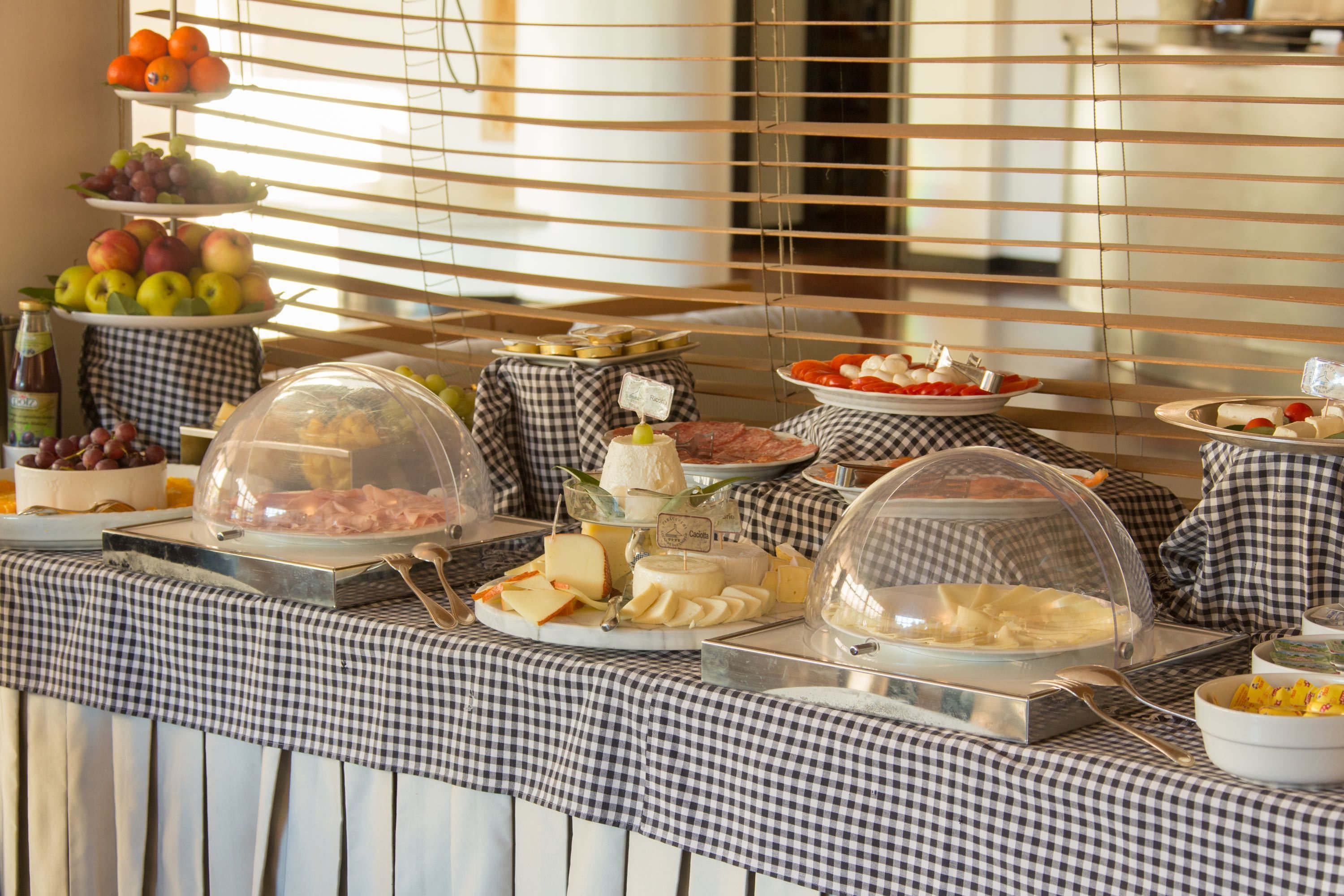 Un buffet proposant une variété de plats, notamment des fruits, des fromages et des viandes, présentés sous des cloches de verre.