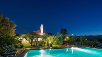 Una piscina al aire libre, sombrillas, sillones reclinables de piscina