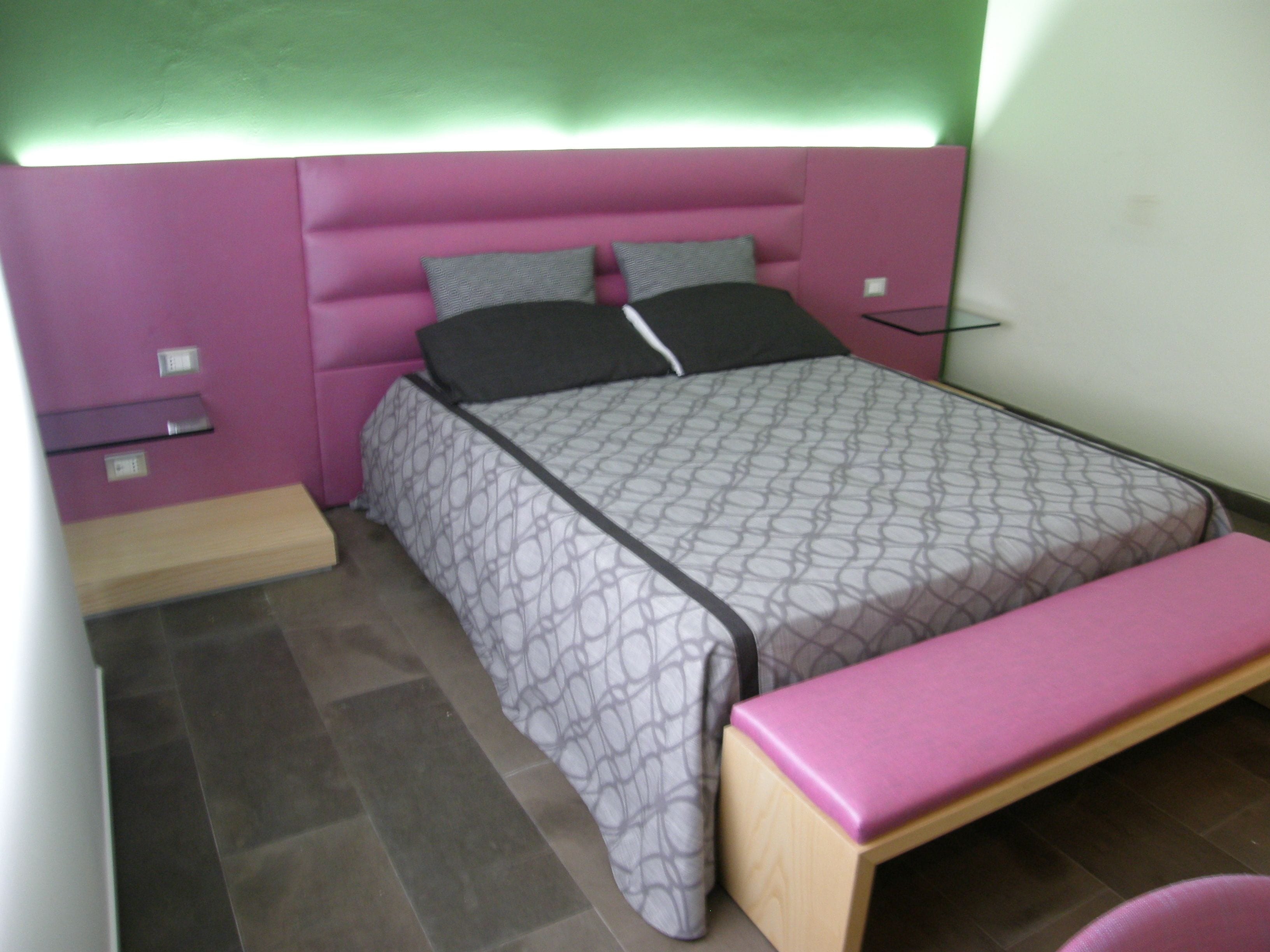 Un dormitorio pequeño y ordenado con cama, mesitas de noche y un banco.