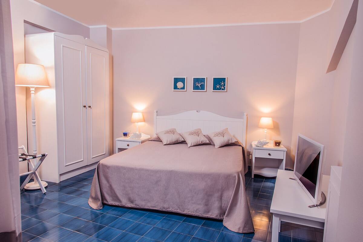 A bedroom with a bed, nightstands, a TV, and a wardrobe.