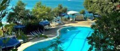 Una piscina al aire libre, cabañas de piscina (de pago)