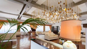Un hall d’entrée spacieux, agrémenté d’un lustre moderne, de sièges confortables et d’un grand vase posé sur le comptoir de la réception.
