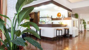 A bar area with stools, a counter, and shelves with bottles.