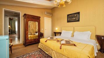 A hotel room with a large bed, a wooden wardrobe, a mirror, a chandelier, and a patterned rug.