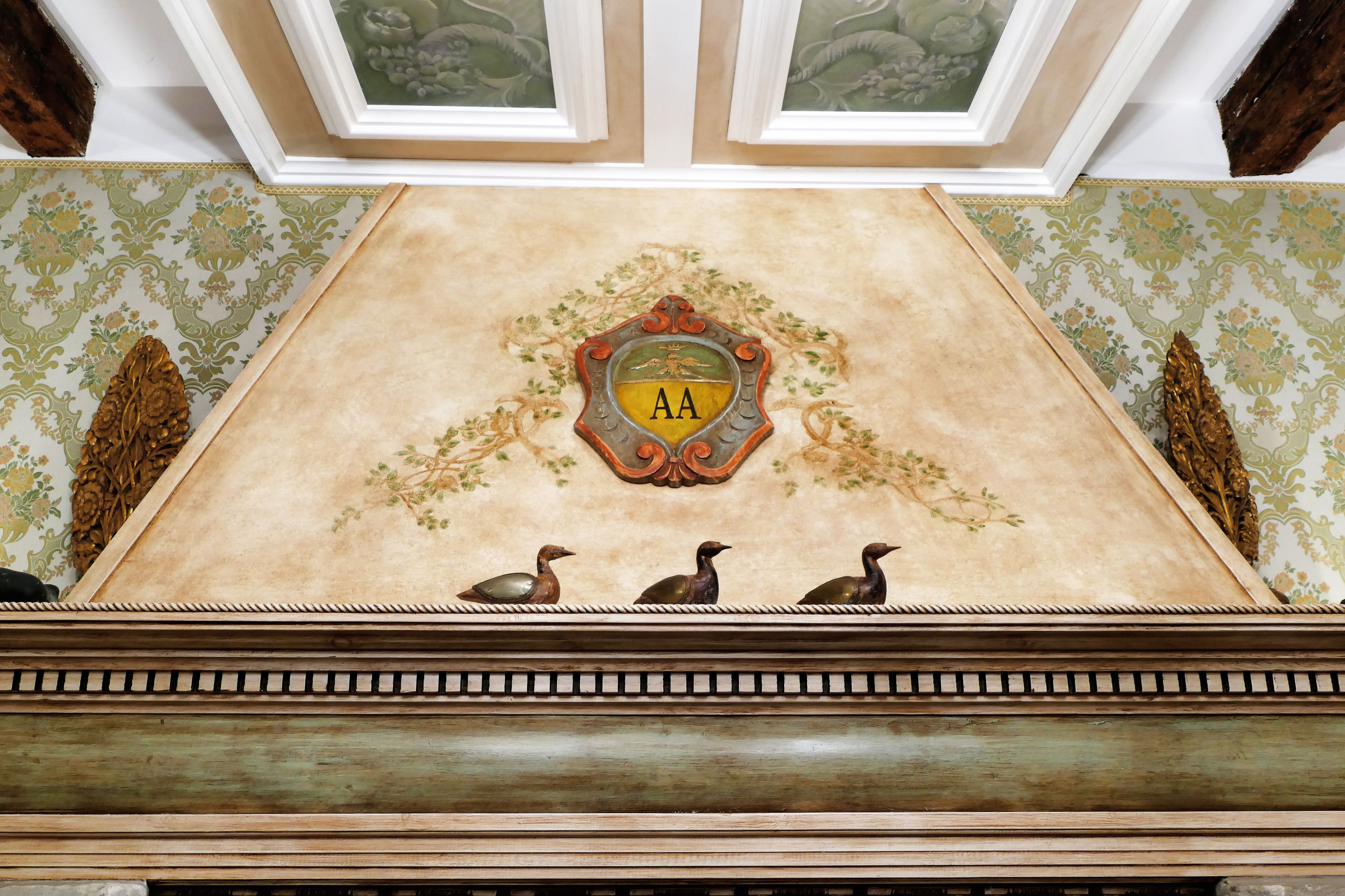 A ceiling with a decorative emblem featuring the letters "AA" and three ducks.