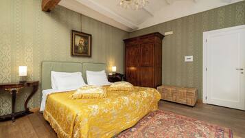 A bedroom with a large bed, a wooden wardrobe, a nightstand, and a patterned rug.